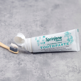 sprinjene fluoride free toothpaste being applied to charcoal tooth brush